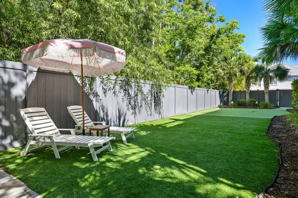 the grand palmetto back yard with putting green, sun loungers, umbrellas and a grill